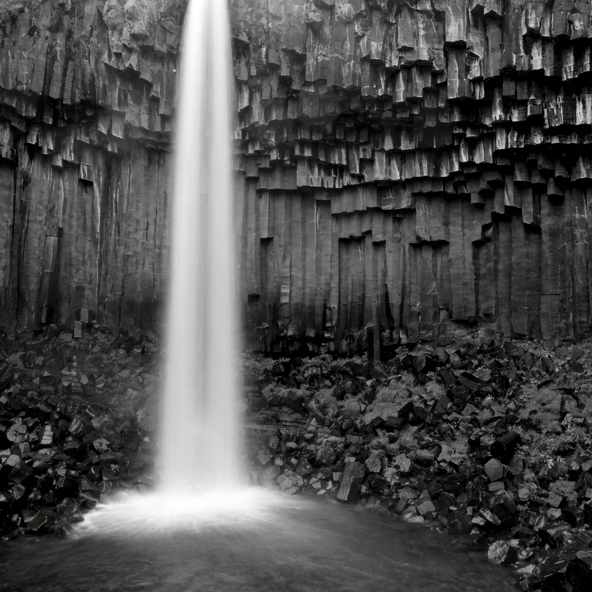 Ein Wasserfall inmitten von schwarzem Gestein.